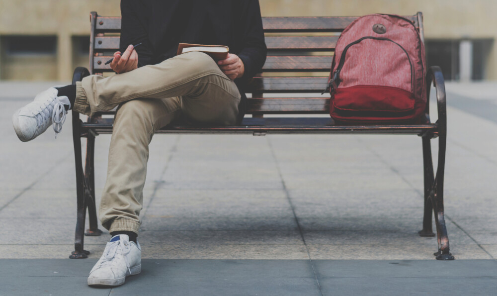 Young male sitting on a bench seat with backpack (1)
