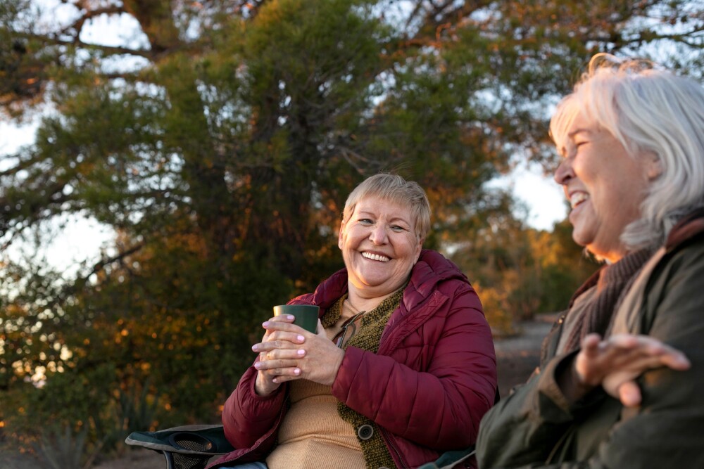two senior women nature escapade sitting chairs enjoying their time resized